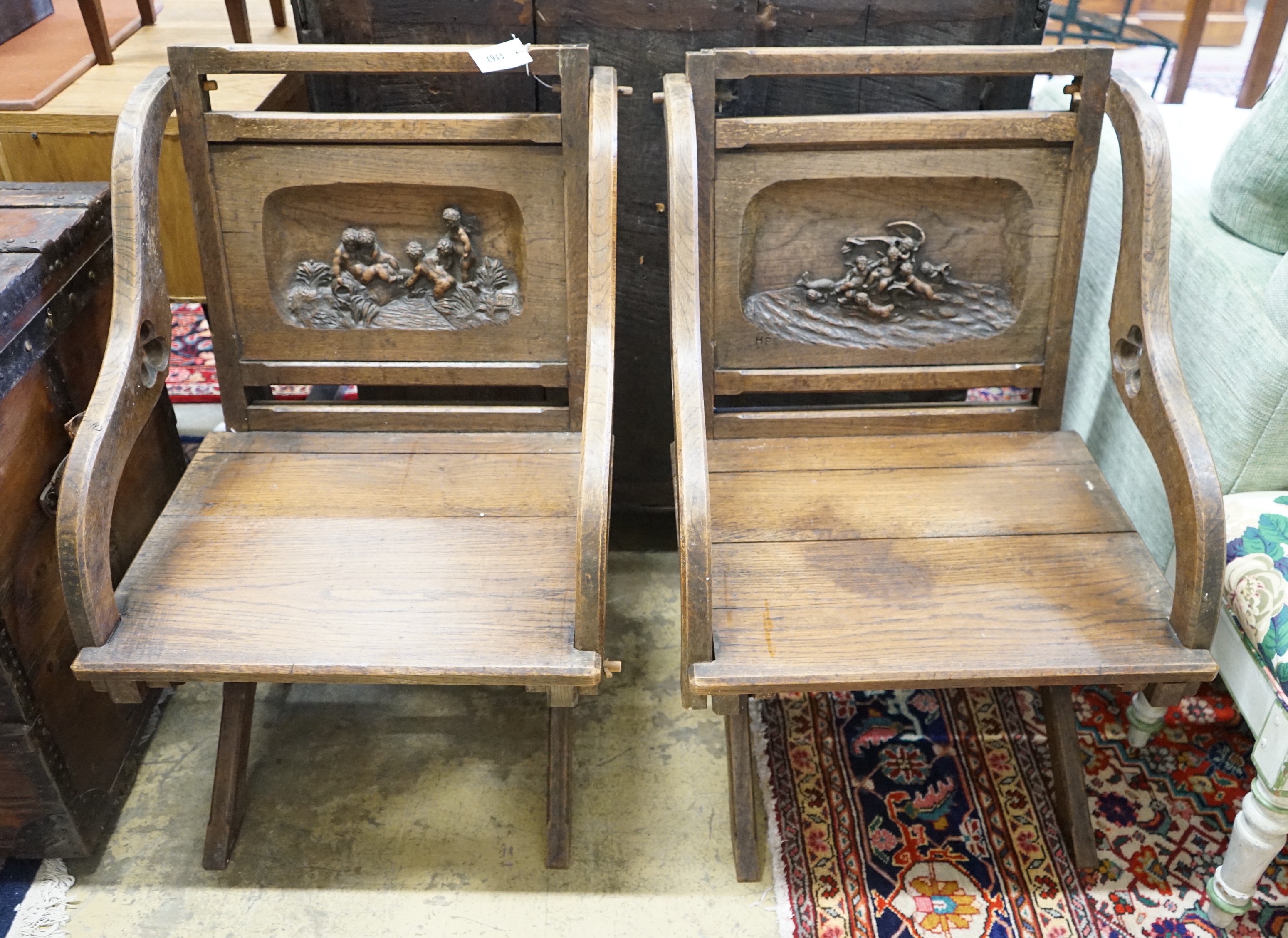A pair of carved oak Glastonbury type chairs, width 58cm, depth 48cm, height 86cm